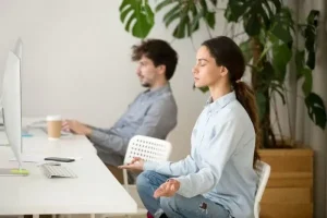 IT más equitativo: 4 estrategias de retención de talentos mujeres 7 Dos trabajadores en un espacio laboral y una mujer haciendo meditación