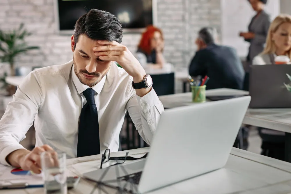 pensive entrepreneur reading business reports while working office there are people background 11zon